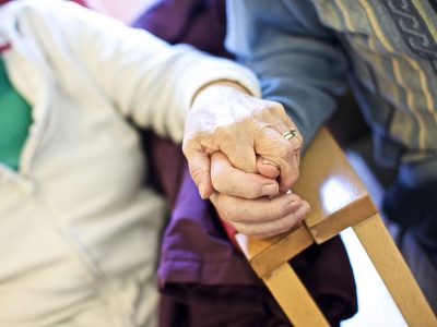 An elderly couple hold hands