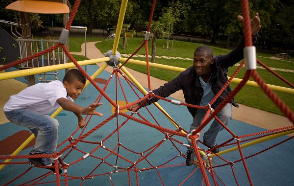 A child and father playing outdoors in a playground