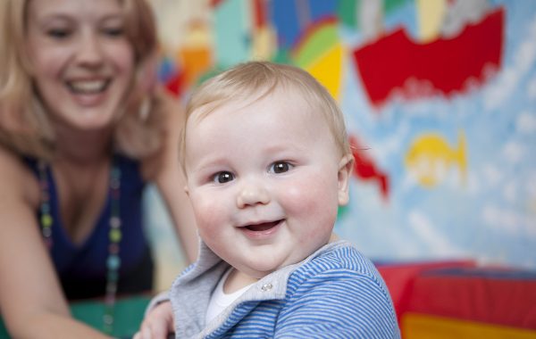 A baby boy in a creche with his mother