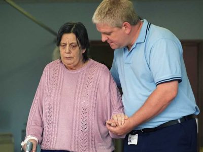 An older woman being helped by a nurse