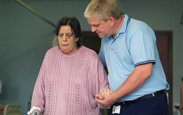 An older woman being helped by a nurse