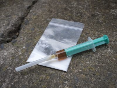 A syringe filled with a brown liquid sitting on top of a drugs bag