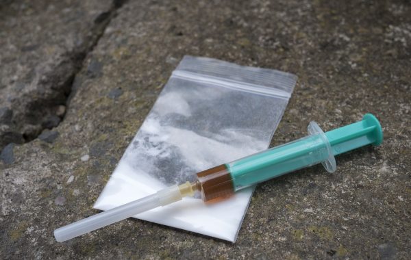 A syringe filled with a brown liquid sitting on top of a drugs bag