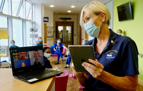An NHS worker in a face mask during an online meeting