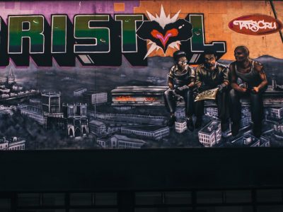 Street art showing the Bristol skyline with three young people sitting in front of it