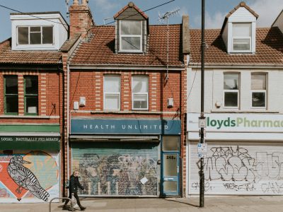 A woman walks down an empty street in Bristol with boarded up shops during the COVID-19 pandemic