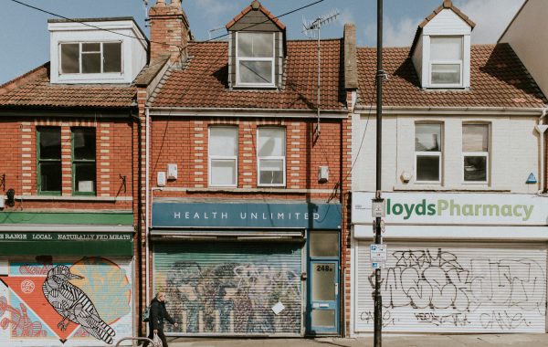 A woman walks down an empty street in Bristol with boarded up shops during the COVID-19 pandemic