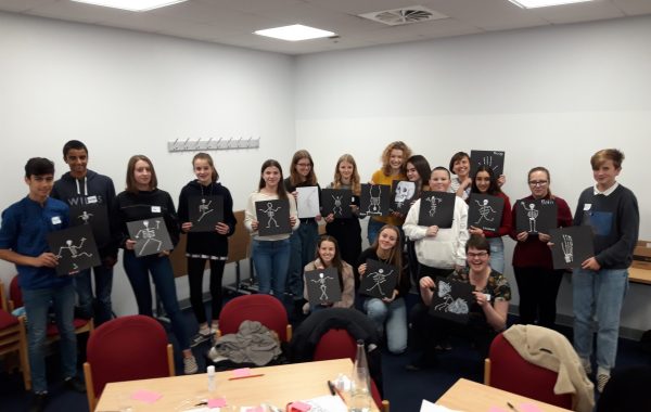 Young people holding up pictures of skeletons