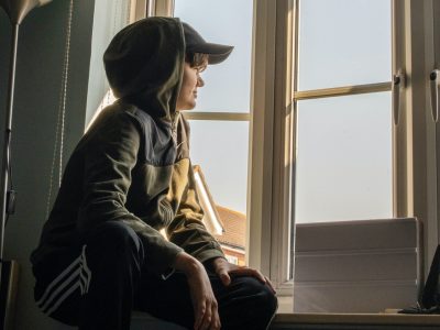 A young person looks out of a window