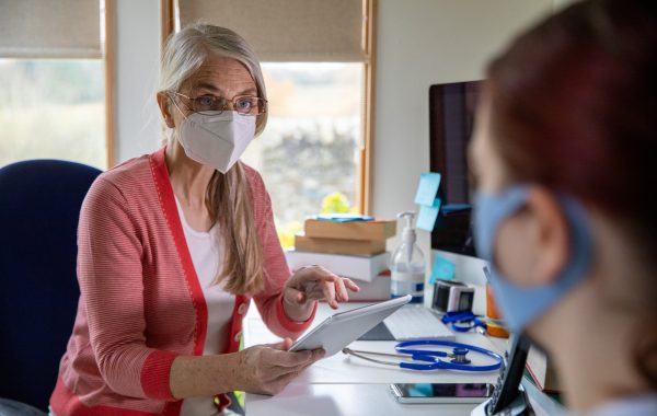 A GP consultation during the COVID pandemic, with both patient and doctor wearing masks