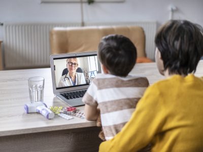 A child and parent on a video call with a doctor