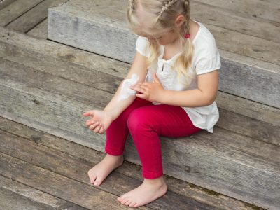 A little girl applies moisturiser to her arm