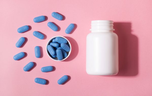 Selection of blue PrEP tablets laid out next to a white bottle