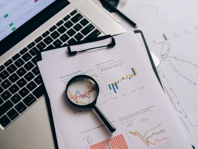 Graphs on a clipboard with a magnifying glass to suggest analysis