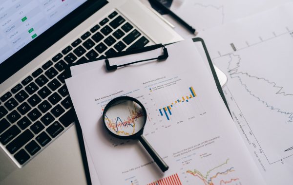 Graphs on a clipboard with a magnifying glass to suggest analysis