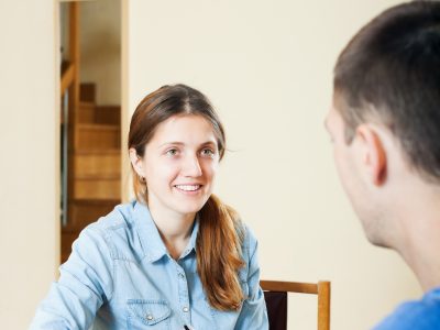 A young woman talks to a man while taking notes