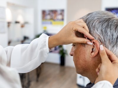 A man is being fitted with a hearing aid at an audiology clinic