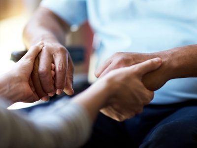 Closeup shot of a young woman holding a senior man's hands in comfort