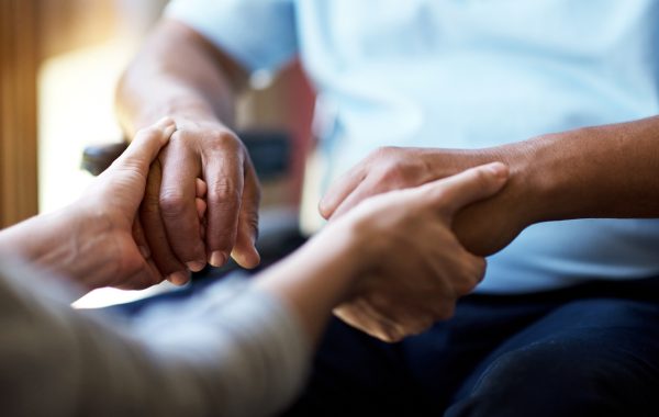 Closeup shot of a young woman holding a senior man's hands in comfort