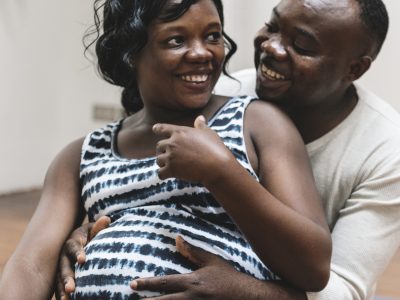 A Black pregnant woman laughs with her partner