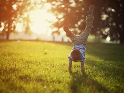 A little boy is doing a handstand on some grass