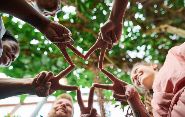 A group of children is holding their hands together in the victory sign