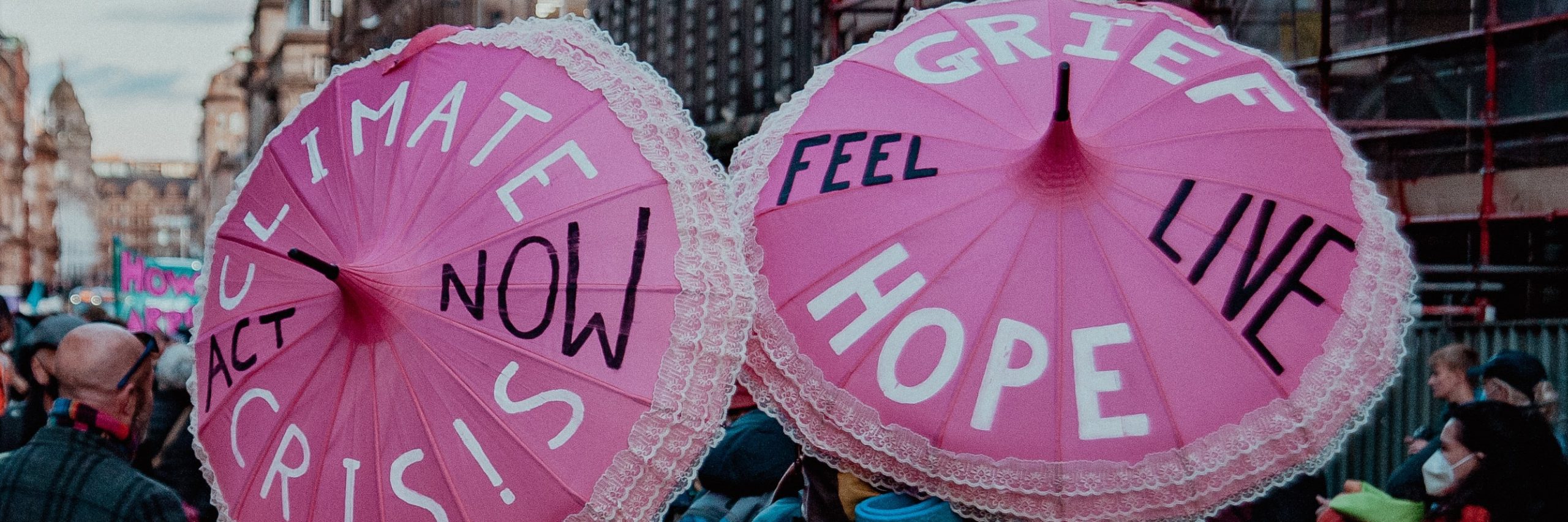 Climate change protesters hold up umbrellas inscribed with the words: "Climate, Crisis, Act Now" and "Grief, Hope, Feel, Live".