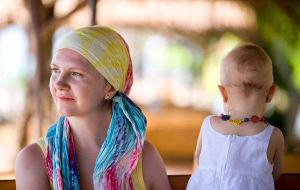 A mother wearing a headscarf is sitting on a bench enjoying a moment with her young daughter