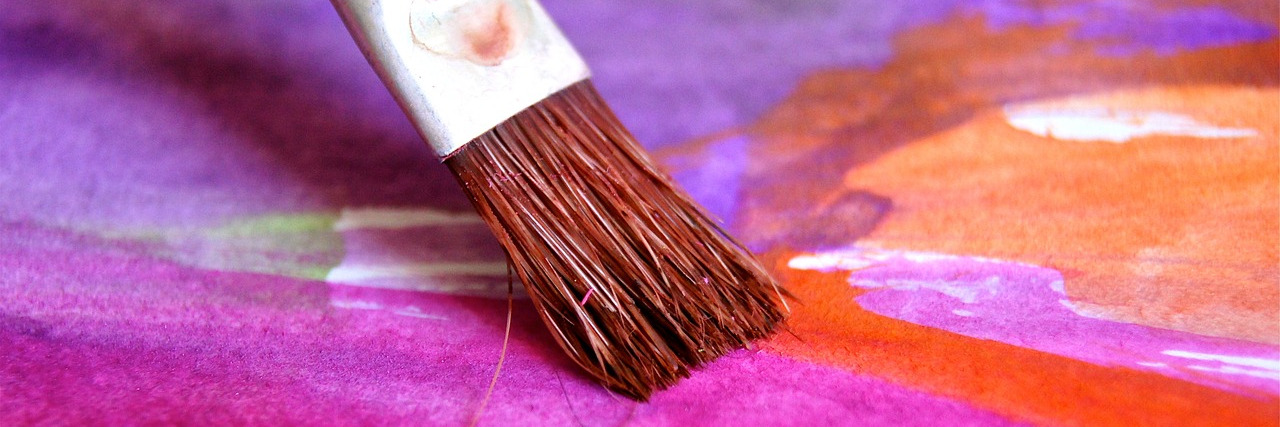 Close up of a paintbrush painting bright watercolours