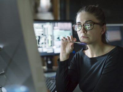 A researcher sits at a computer looking thoughtful