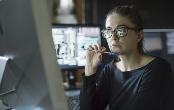 A researcher sits at a computer looking thoughtful
