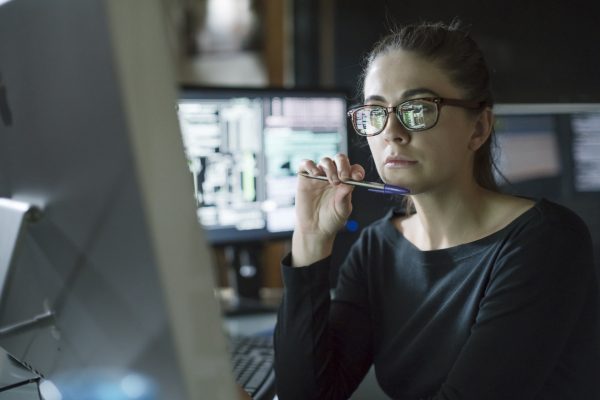 A researcher sits at a computer looking thoughtful
