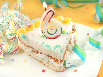 Slice of birthday cake with a number 6 candle on top