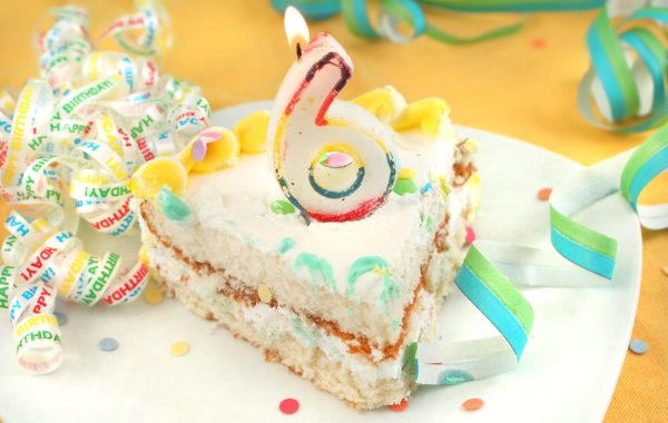 Slice of birthday cake with a number 6 candle on top